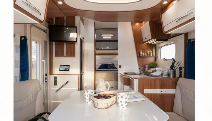 Modern RV rental interior, featuring a bright kitchen, dining table, and a glimpse of the bedroom. Ideal for camper adventures.. PILOTE P726 C 2026