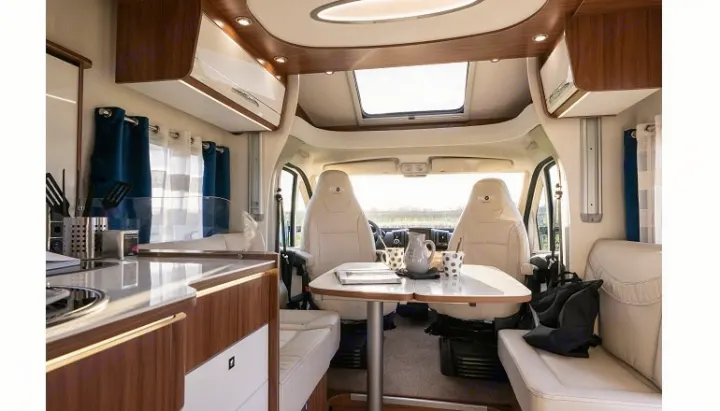 Cozy RV rental interior with a functional kitchen, dining table, and front cabin seats, ready for adventure.. PILOTE P726 C 2026