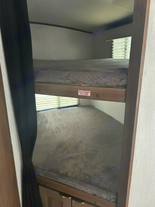 Cozy RV rental bunk beds with a privacy curtain, offering extra sleeping space. Upper bunk has a 275 lb max weight.. Cruiser RV MPG 2023