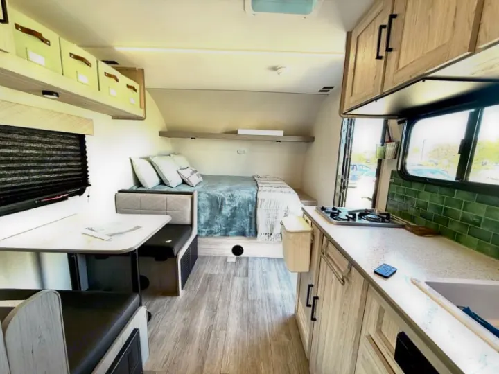 Spacious rv rental interior featuring a bed, dinette, kitchen with green subway tile, and light wood cabinetry. Comfort on wheels!. Heartland RVs Mallard 2025