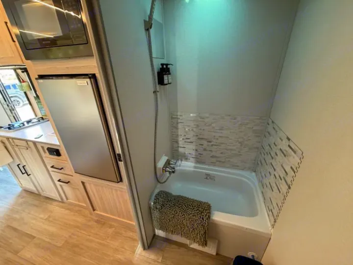 This RV rental offers a compact kitchen with a microwave, fridge, and stove, plus a modern bathroom with a tub and shower.. Heartland RVs Mallard 2025