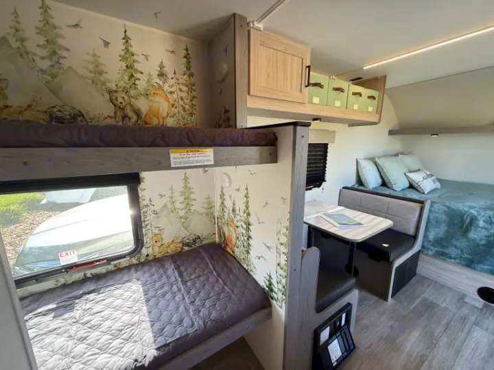Family-friendly RV rental interior with forest-themed bunk beds, dinette, and main bed. Perfect for adventure.. Heartland RVs Mallard 2025