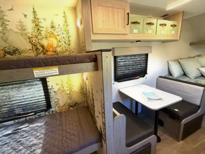 Inside a family RV rental: bunk beds with a nature-themed wall mural, a dinette, and a sofa.. Heartland RVs Mallard 2025