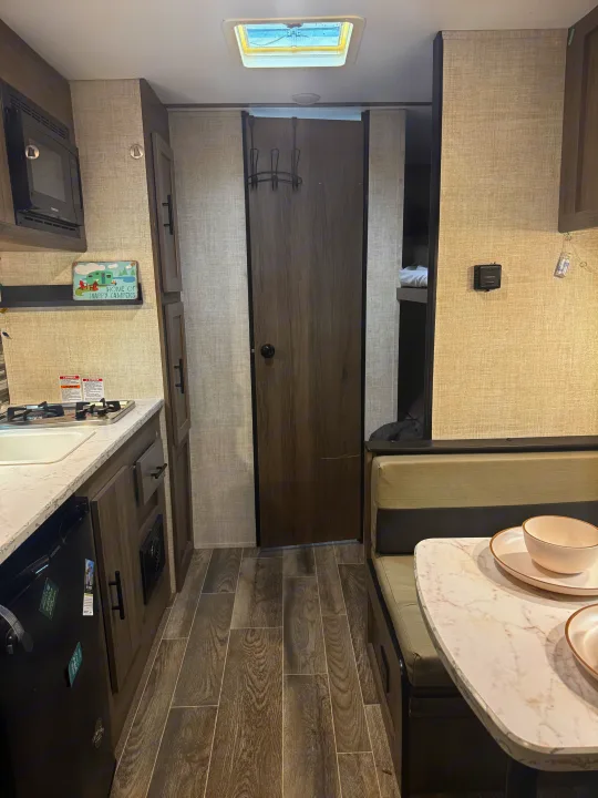 Cozy RV rental interior showcasing kitchen, dinette, and bunk beds. Perfect for your next adventure.. Gulf Stream Enlighten 2021
