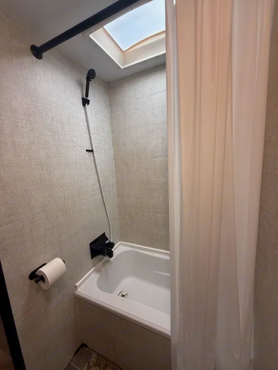 RV rental bathroom with compact shower/tub, toilet paper holder, skylight, and white shower curtain.. Gulf Stream Enlighten 2021