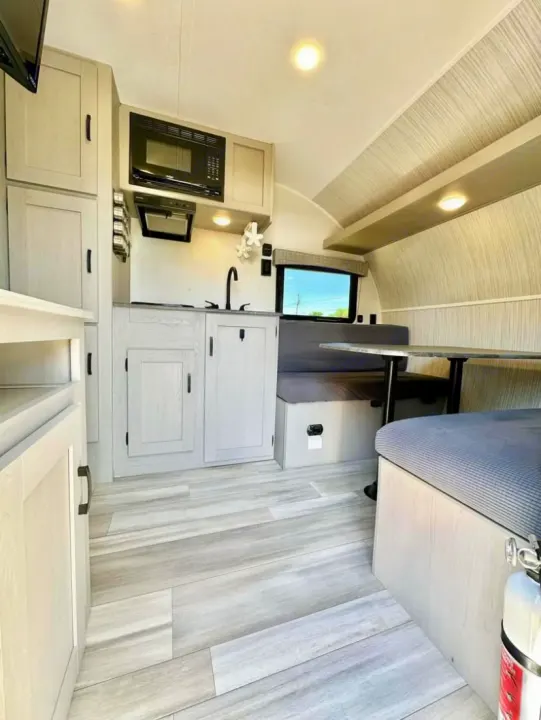Modern and compact RV rental interior featuring a bright kitchen, cozy dinette, and wood-look flooring.. Clipper 3K 2023