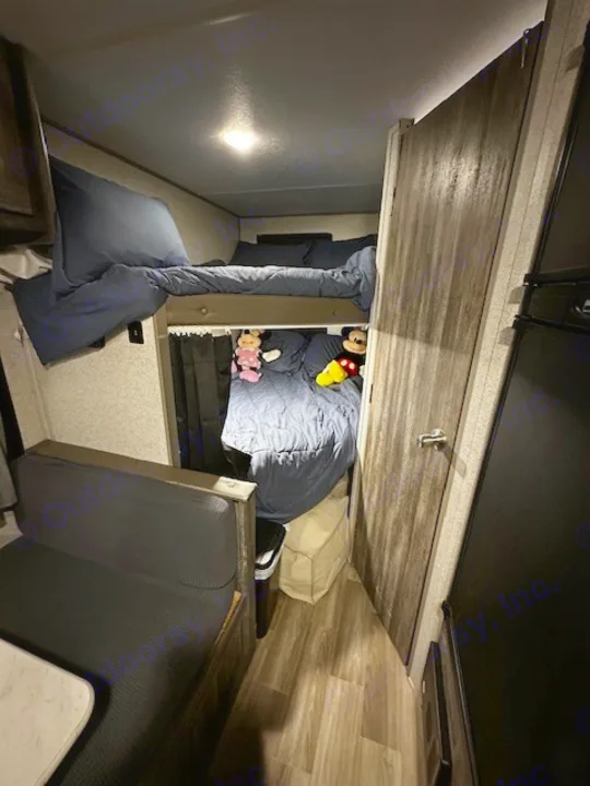 Cozy RV rental interior showcasing bunk beds with blue bedding, a dinette, and fun Mickey & Minnie plushies.. Forest River Salem FSX PLATINUM 2020