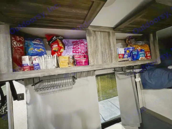 An RV rental's overhead pantry, packed with chips, crackers, cereal, and tuna for road trip snacks and meals.. Forest River Salem FSX PLATINUM 2020