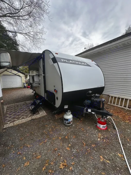 This Platinum RV rental travel trailer, with awning out & propane ready, is parked on a gravel driveway, perfect for camping.. Forest River Salem FSX PLATINUM 2020