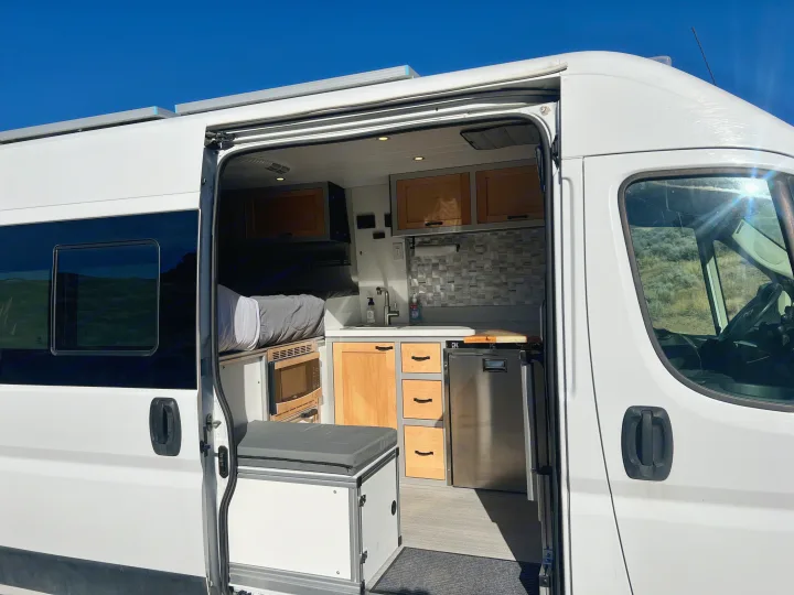 Inside this RV rental camper van: custom interior with kitchen, bed, fridge, and storage, ready for adventure.. Ram Promaster 1500 2020