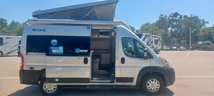 Silver Scope camper van with open door and pop-top roof, ready for an RV rental adventure.. Thor Scope 2023