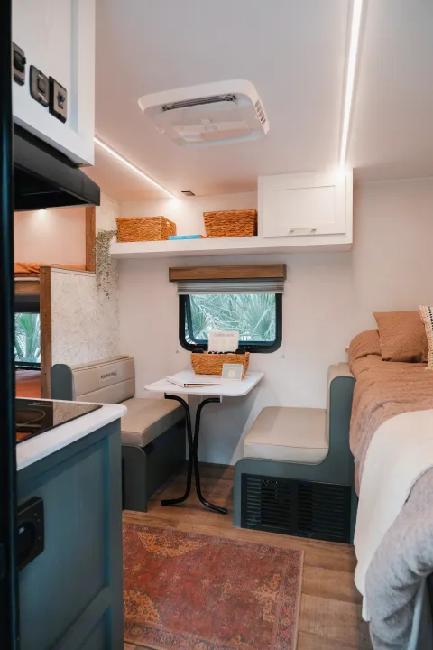 A bright and modern RV rental interior, showcasing a dinette, cozy bed, and functional kitchen with stylish decor.. Heartland RVs Eddie Bauer 2025