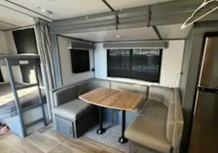 Interior of an rv rental: U-shaped dinette, bunk beds with ladder, and refrigerator. Ideal for family trips.. Keystone RV Bullet Ultra Lite 2022