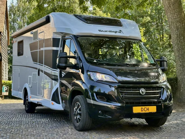 Sleek black & gray motorhome, ideal for rv rental adventures. Parked on cobblestones, surrounded by lush trees.. Sunlight T69LC Adventure 2026