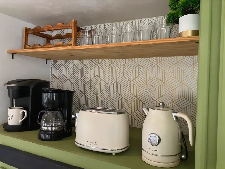 RV rental's compact coffee station: coffee maker, toaster, & kettle on green counter, with glasses & geometric backsplash.. Highland Ridge RV Roamer 2017