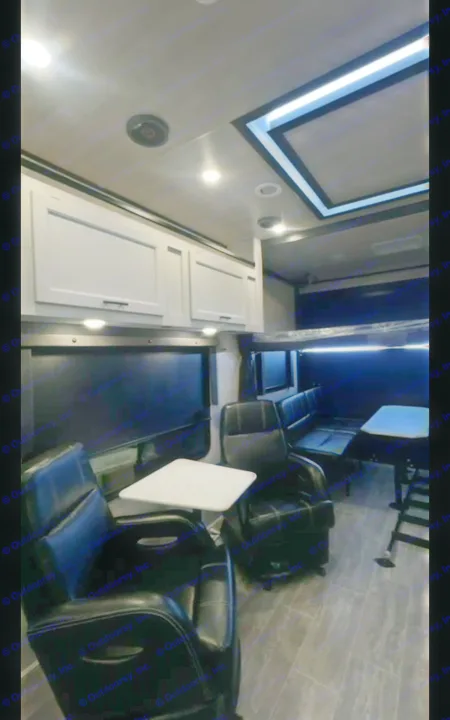 Modern RV rental living space featuring comfortable black recliners, a dinette, overhead storage, and stylish lighting.. Genesis Supreme Rv Genesis Supreme 2026