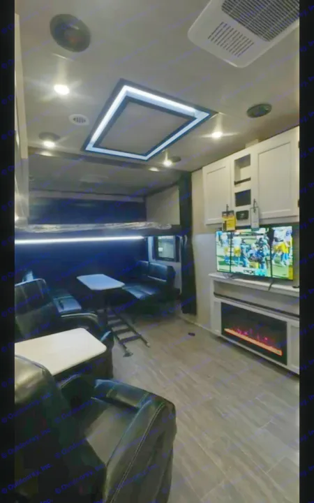 Spacious RV rental interior with recliners, a large TV over an electric fireplace, and contemporary ceiling lights.. Genesis Supreme Rv Genesis Supreme 2026