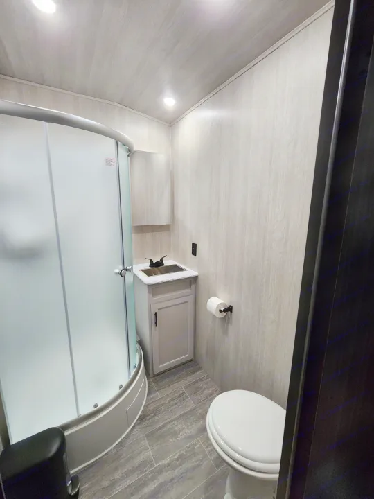 This RV rental bathroom offers a compact, modern design with a curved frosted shower, vanity, and toilet. Bright, clean interior.. Genesis Supreme Rv Genesis Supreme 2026