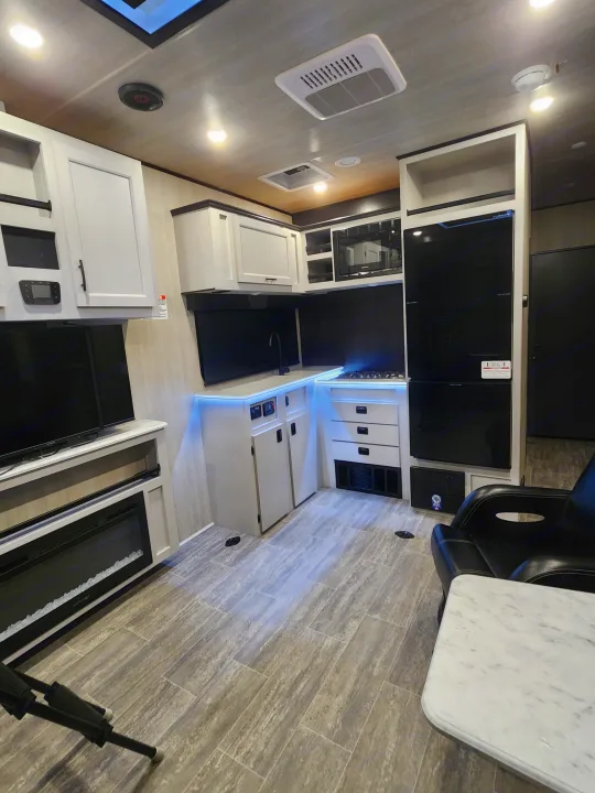 Spacious RV rental kitchen & living area with modern appliances, fireplace, and lounge seating, featuring sleek design.. Genesis Supreme Rv Genesis Supreme 2026