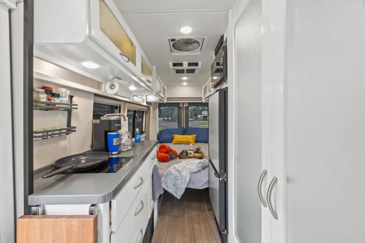 This cozy RV rental interior features a compact kitchen, comfortable bedroom, and all the amenities for travel.. Coachmen Beyond 2021