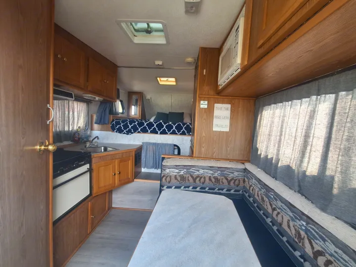RV rental interior: cozy kitchen with stove/sink, dinette, and an overhead bed for travel adventures.. Glacier Campers Truck Camper 2016