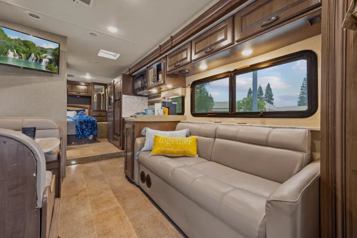 RV rental interior: A cozy living area with a couch, TV, kitchen, and a view into the bedroom, offering comfortable travels.. Thor Motor Coach Chateau 2019
