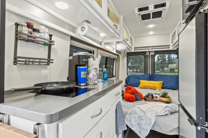 Enjoy this RV rental's cozy interior, featuring a compact kitchen with a Keurig and a comfortable bed setup for your travels.. Coachmen Beyond 2021