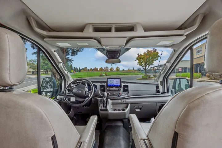 RV rental van interior: Driver's cabin view with dashboard, Ford steering wheel, and clear road ahead through the windshield.. Coachmen Beyond 2021