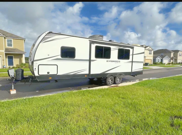 White Embrace Ultra Lite travel trailer, a great RV rental for exploring, parked on a street near suburban homes.. Cruiser RV Embrace Ultra Lite 2022