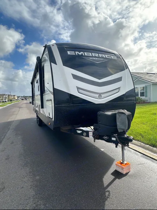 An Embrace Ultra-Lite travel trailer RV rental, parked on a street with leveling blocks under its hitch, ready for adventure.. Cruiser RV Embrace Ultra Lite 2022