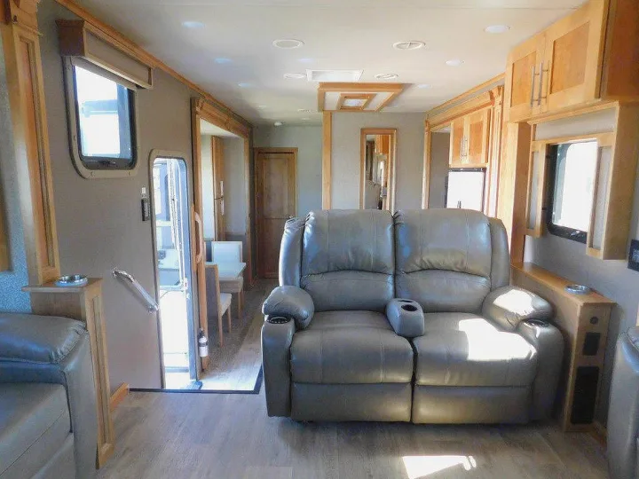RV rental interior: A cozy living space with a gray recliner sofa, light wood cabinets, and natural light from windows.. Vanleigh RV Vilano 2018