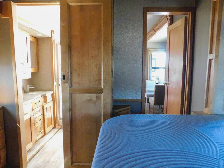RV rental interior: blue bed, pocket door to bathroom vanity, and hinged door reveals a bright living space.. Vanleigh RV Vilano 2018