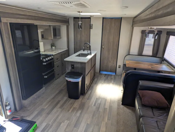 Modern rv rental interior featuring a full kitchen with island, cozy dining booth, and comfortable living area.. Forest River Vibe 2020