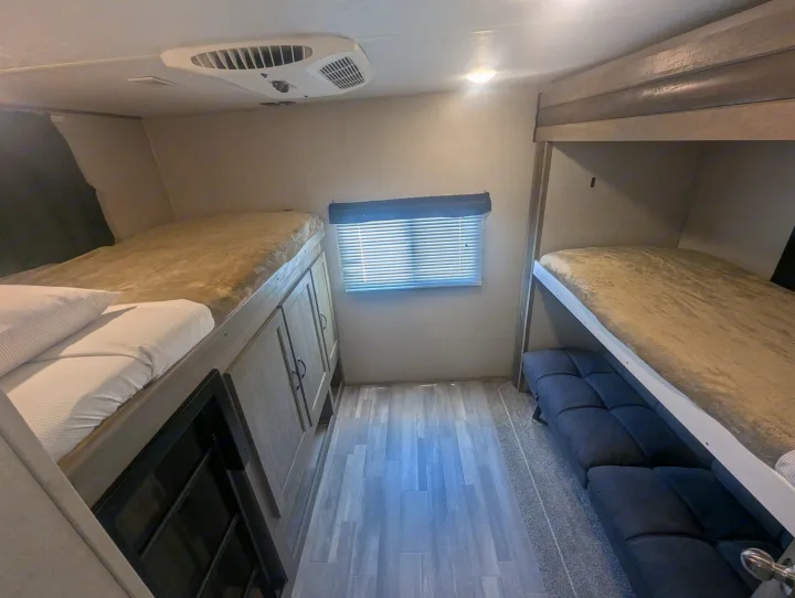 Explore this RV rental's sleeping area with dual bunk beds, ceiling AC, window, and storage for comfortable trips.. Forest River Vibe 2020