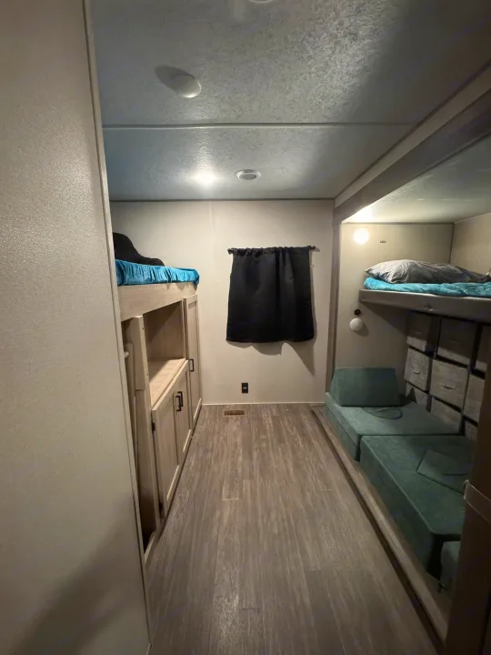 View inside an RV rental's bunk room, showing beds, modular green seating, and built-in storage.. Forest River Aurora Aurora 2024