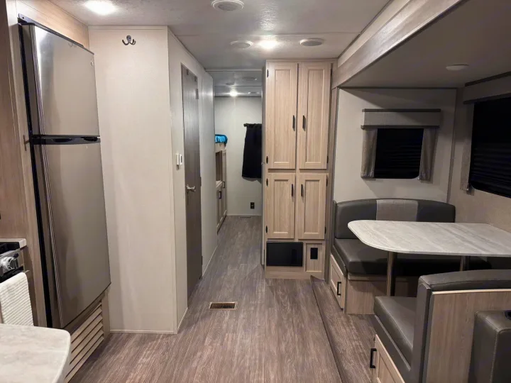 This spacious and modern RV rental interior features a kitchen, dining area, and hallway leading to bunk beds.. Forest River Aurora Aurora 2024