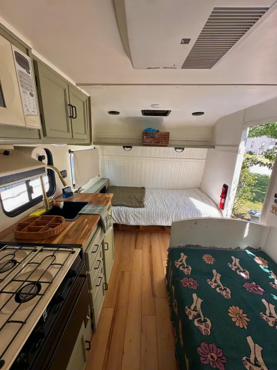 Cozy, renovated RV rental interior with a modern kitchen, wood flooring, and comfortable sleeping nooks.. Coachmen Catalina 1994