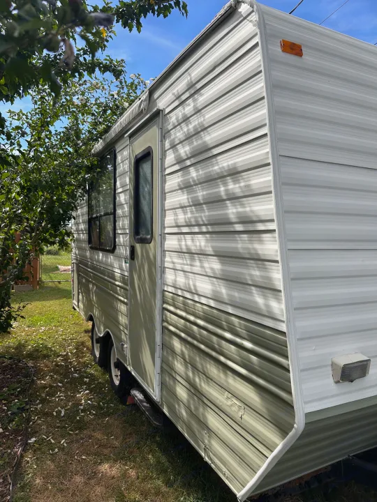 Green and white striped travel trailer parked outdoors on a sunny day, an ideal option for your next RV rental.. Coachmen Catalina 1994