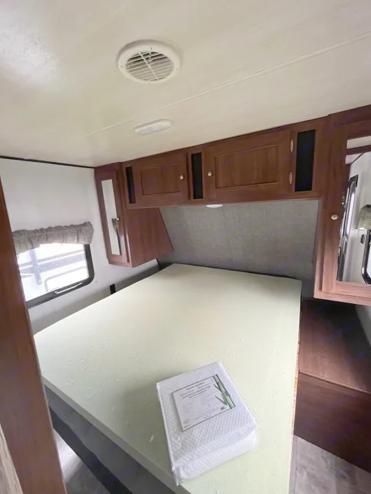 RV rental bedroom with clean foam mattress, new bamboo protector, overhead storage, and window. Ready for your adventure.. Pioneer Bunkhouse 2019