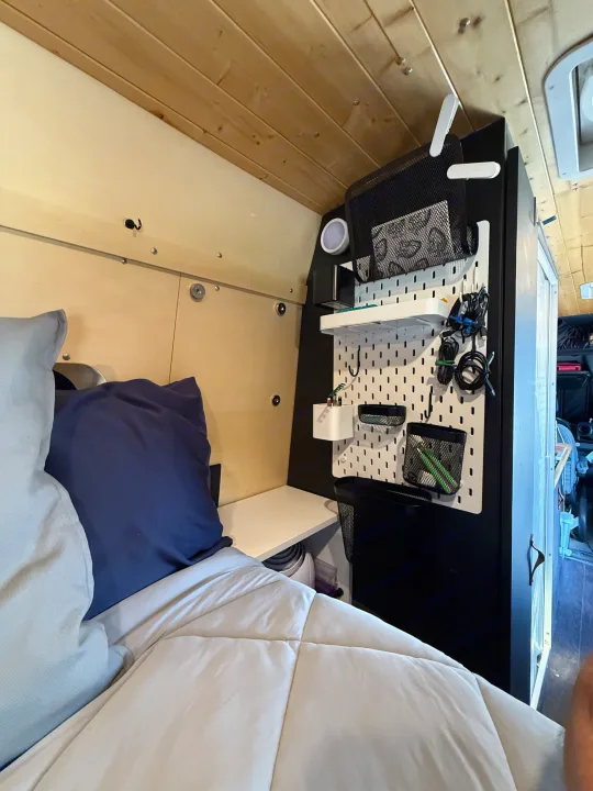 Cozy rv rental interior featuring a bed, an integrated nightstand, and a pegboard organization system for efficient storage.. Mercedes-Benz Sprinter 2019