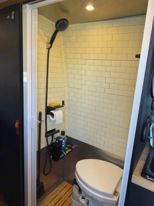 RV rental bathroom featuring yellow subway tiles, a shower, and a composting toilet setup for van life.. Mercedes-Benz Sprinter 2019