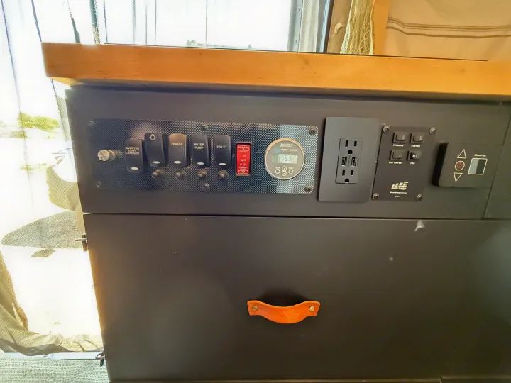RV rental's control panel: Switches for inverter, fridge, water pump, lights, and toilet. Also, a battery monitor, outlets, and climate controls.. Mercedes-Benz Sprinter 2019