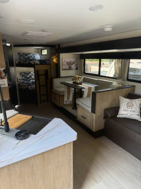 Cozy rv rental interior with bunk beds, dinette, sofa, and kitchen counter, perfect for family adventures.. Forest River Grey wolf 2026