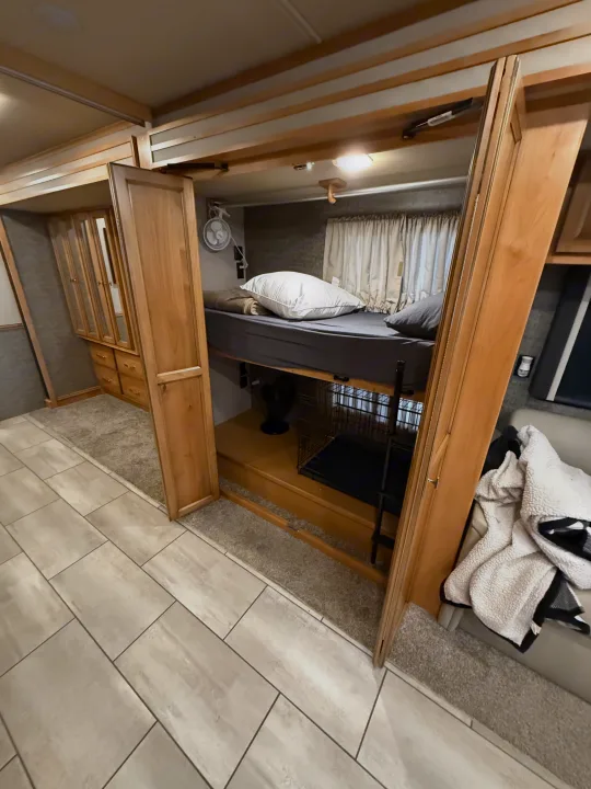 This RV rental features a practical bunk bed with a dog crate below, ample storage, and comfortable interior design.. Tiffin Allegro 2020
