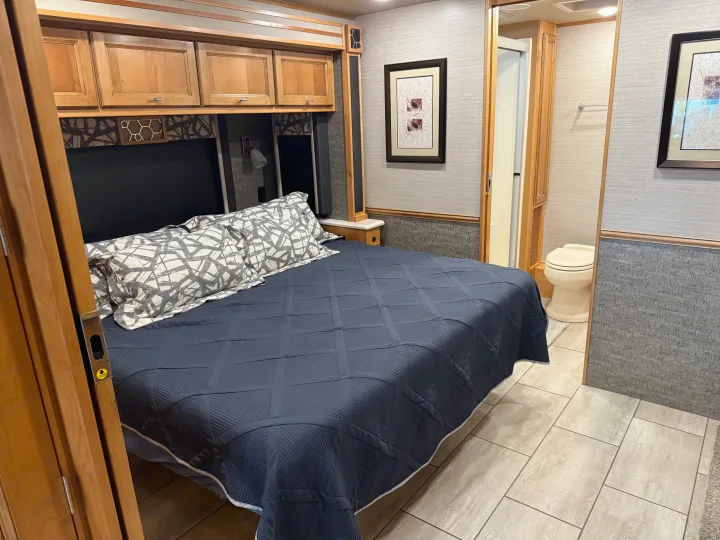 Spacious RV rental bedroom with bed, overhead storage, and adjacent bathroom.. Tiffin Allegro 2020