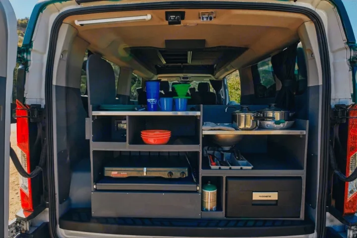 This RV rental camper van features a compact, fully-equipped kitchen with a stove, sink, and Dometic cooler, perfect for camping gear.. Ford Transit 2017