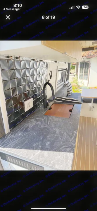 RV rental kitchen: modern black faucet, dark swirled countertop, 3D tiled backsplash, and versatile sink with wooden cover.. Mercedes Sprinter 2022