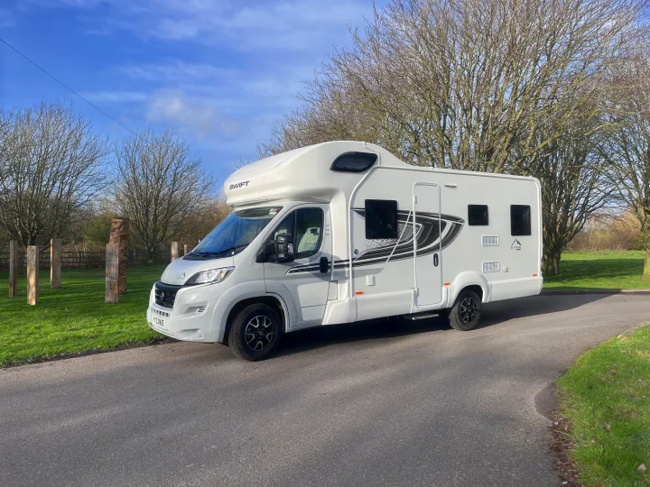White Swift motorhome on a sunny day, ready for an rv rental adventure amidst bare trees and green grass.. Swift Edge 486 2024