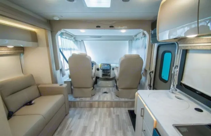 Spacious rv rental interior with a modern kitchen, comfortable sofa, and front cockpit area visible.. Axis 24.1 2027