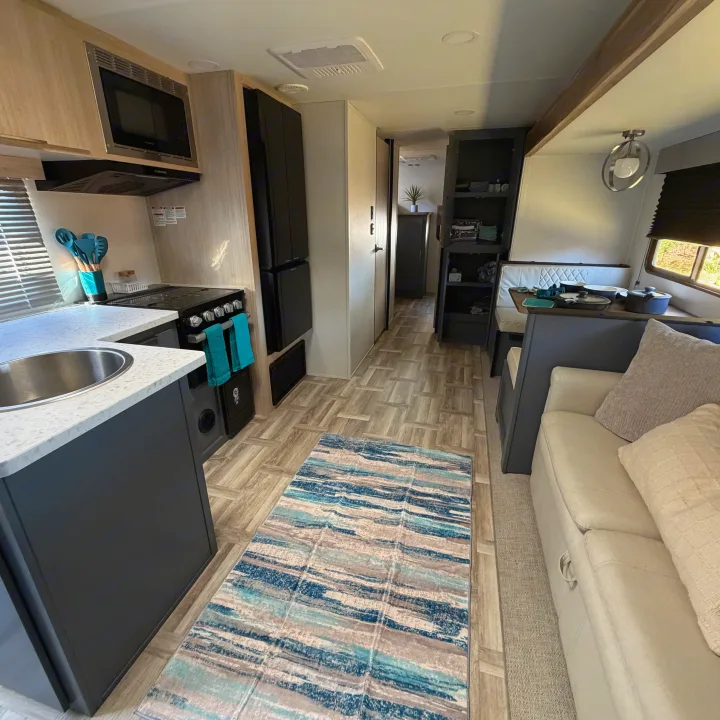 Bright rv rental interior with a sleek kitchen, comfy sofa, dining area, and wood-grain floor for a cozy stay.. Forest River Tracer Ultra Lite LE 2025